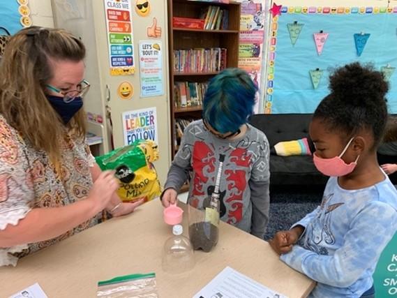 Science Education Team Member demonstrating soil experiment with elementary students